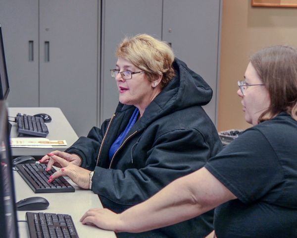 Librarian working one-on-one with an adult on the computer