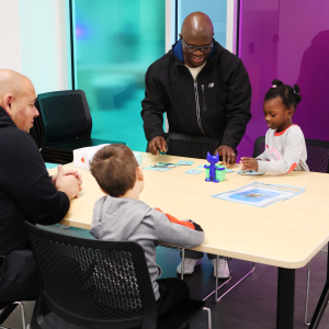 Children and their caregivers work on a task together on a community table